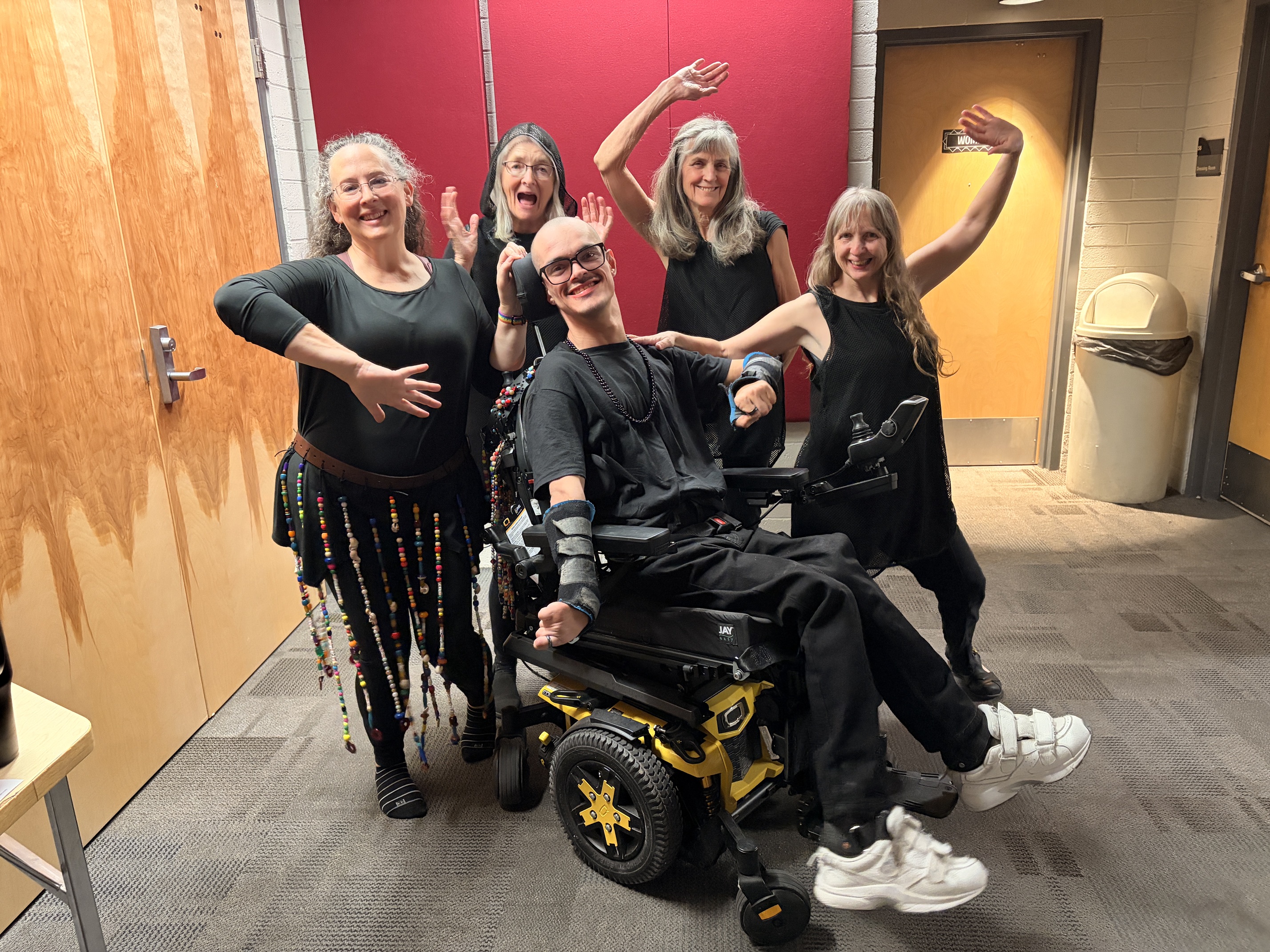 Repertory Company dancers, including a dancer using a power wheelchair, celebrating backstage before a performance