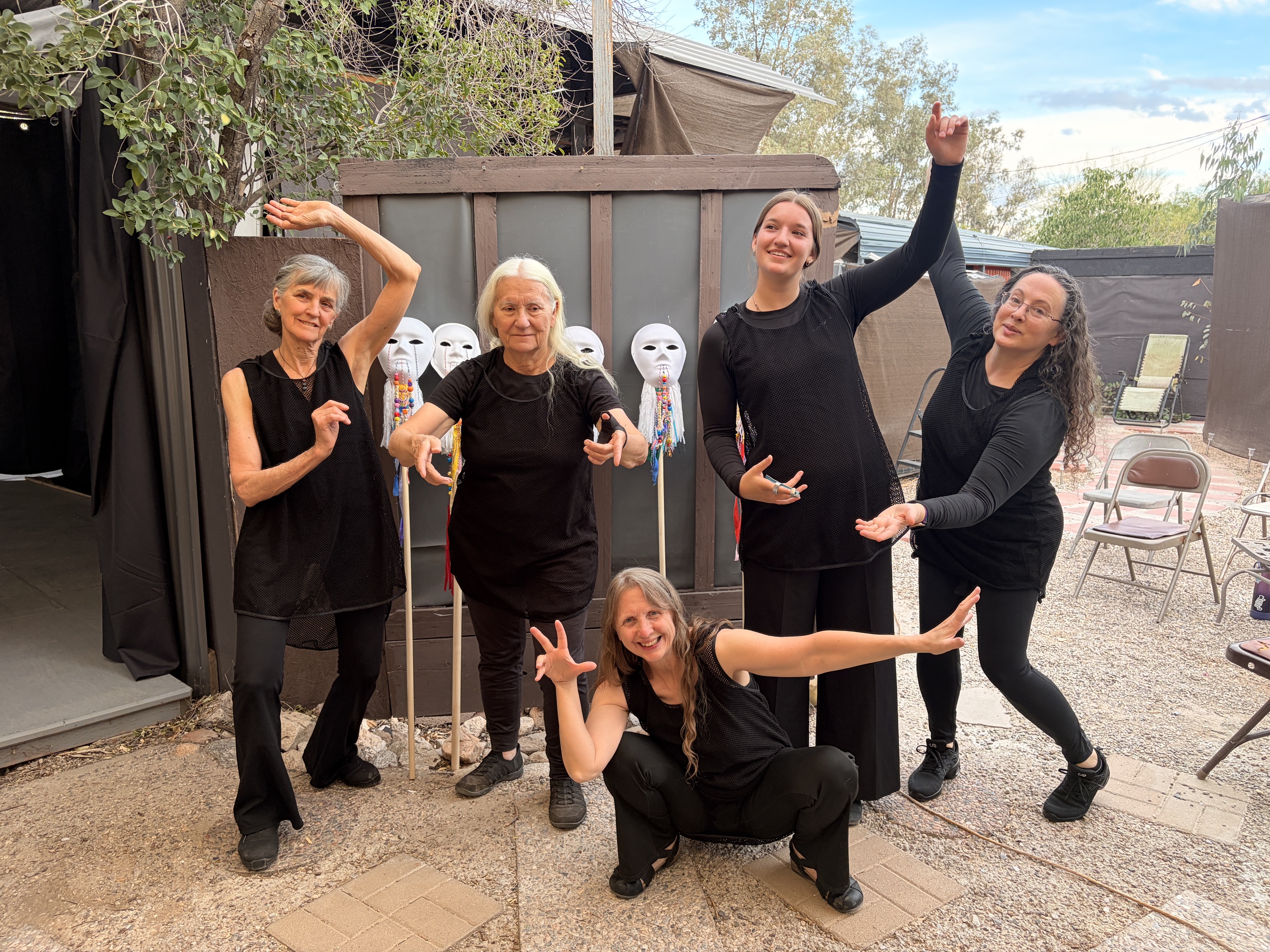 Repertory Company dancers striking playful poses together in a backyard rehearsal space
