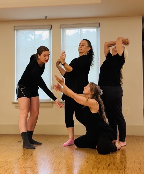 Four dancers improvising together in a studio, arms reaching and extending in different directions